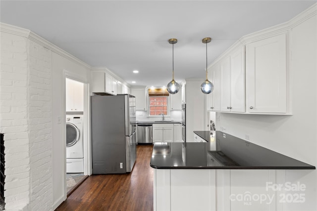 kitchen featuring appliances with stainless steel finishes, a peninsula, white cabinets, washer / clothes dryer, and a sink