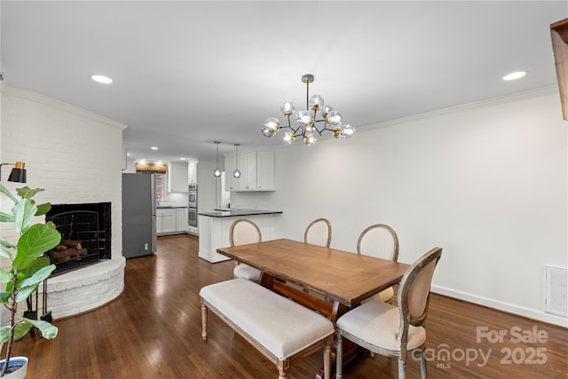 dining room featuring dark wood finished floors, a chandelier, a fireplace, and crown molding