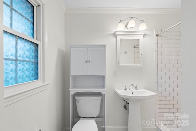 bathroom with a sink, crown molding, toilet, and tiled shower