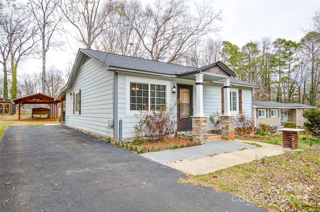 view of front of house with a carport, driveway, and a shingled roof