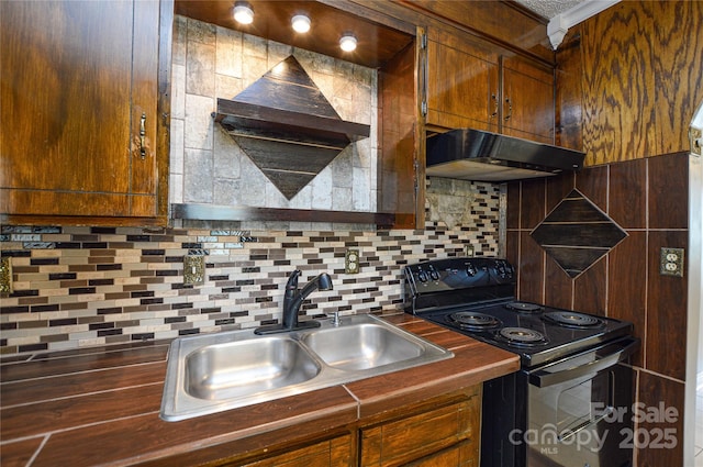 kitchen with black / electric stove, a sink, under cabinet range hood, dark countertops, and tasteful backsplash