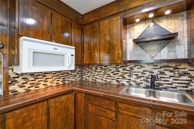 kitchen with a sink, decorative backsplash, wooden counters, and white microwave