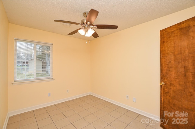 empty room featuring a textured ceiling, light tile patterned flooring, baseboards, and ceiling fan