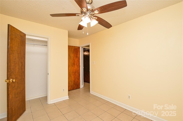 unfurnished bedroom with baseboards, light tile patterned flooring, ceiling fan, a closet, and a textured ceiling