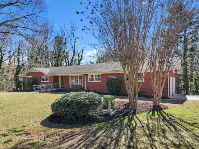 ranch-style home featuring a front yard, a garage, brick siding, and driveway