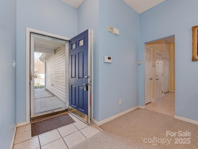 entrance foyer featuring light tile patterned flooring, baseboards, and light carpet