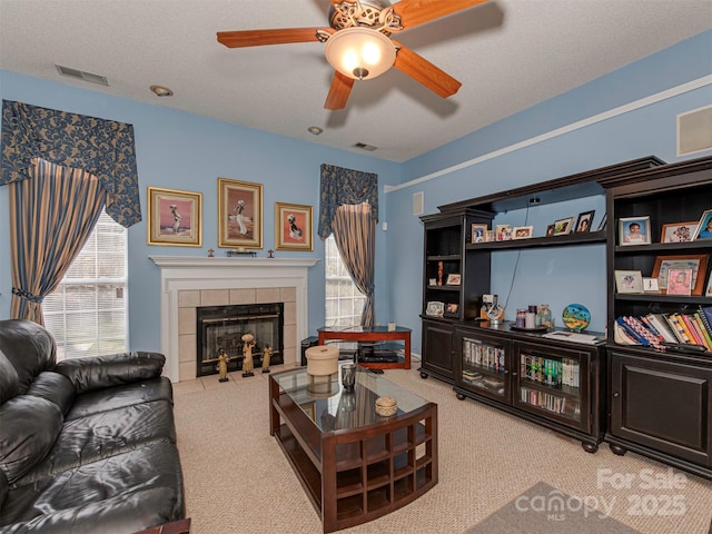 living room featuring a textured ceiling, visible vents, carpet floors, and a tile fireplace