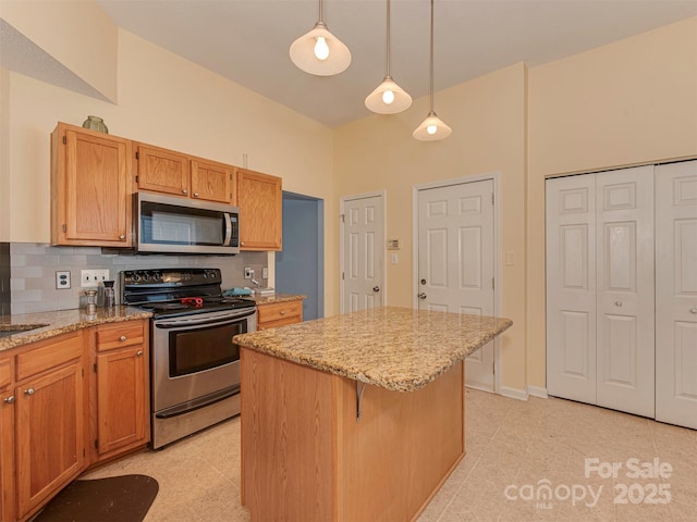 kitchen featuring stainless steel appliances, tasteful backsplash, a kitchen island, and light stone countertops