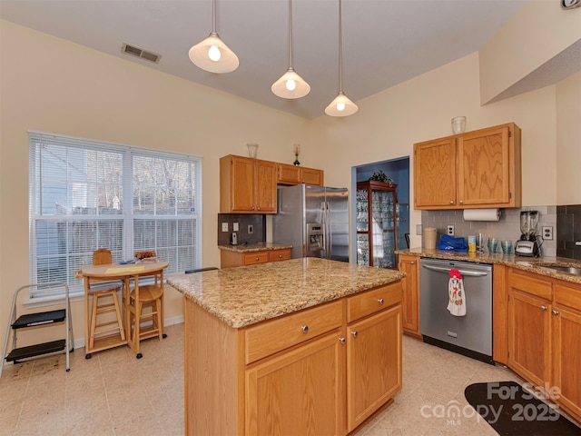 kitchen featuring light stone counters, visible vents, stainless steel appliances, and decorative backsplash