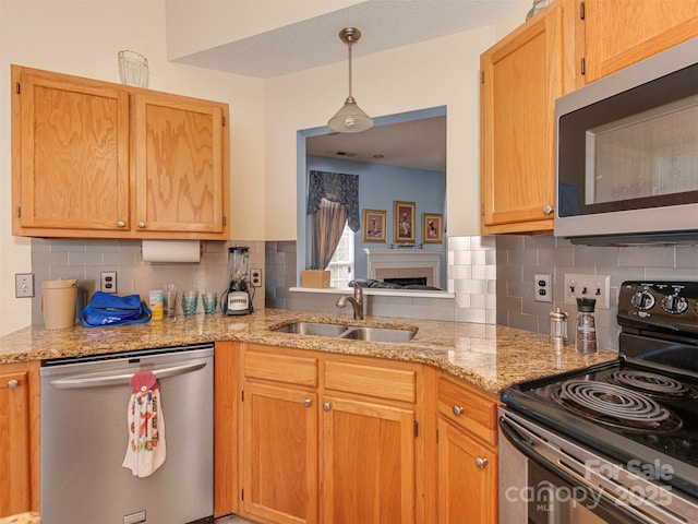 kitchen featuring tasteful backsplash, light stone countertops, stainless steel appliances, and a sink