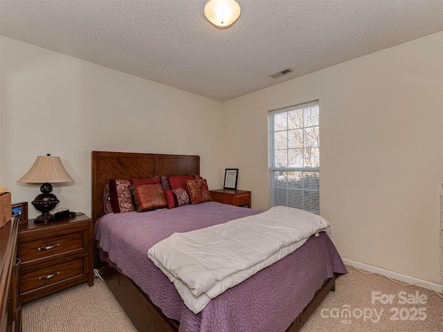 bedroom featuring light carpet, visible vents, a textured ceiling, and baseboards