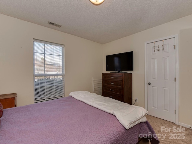 bedroom featuring visible vents, carpet, and a textured ceiling