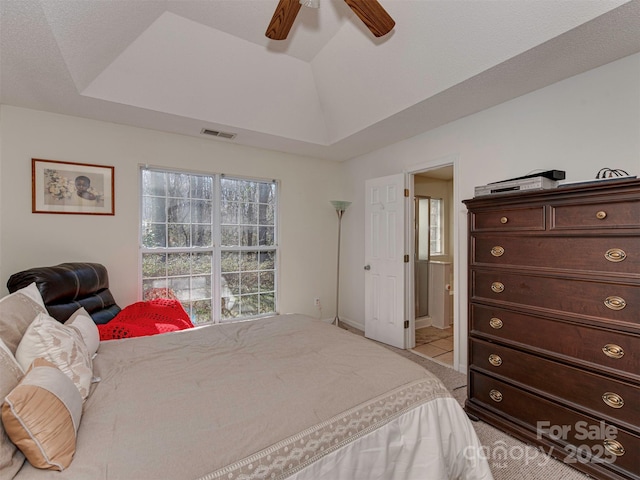 bedroom with a tray ceiling, lofted ceiling, visible vents, and a ceiling fan