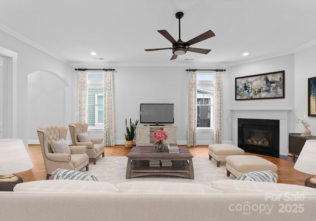 living room featuring a wealth of natural light, a fireplace with flush hearth, and wood finished floors