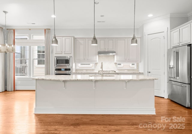 kitchen featuring a breakfast bar area, light wood-style flooring, a sink, ornamental molding, and stainless steel appliances