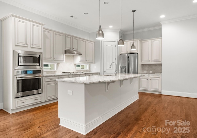 kitchen with under cabinet range hood, appliances with stainless steel finishes, wood finished floors, and a sink