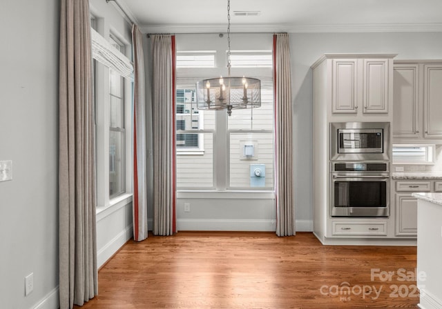 kitchen with visible vents, ornamental molding, stainless steel appliances, light wood-type flooring, and a chandelier