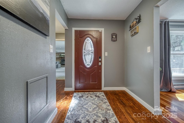 entryway featuring wood finished floors, baseboards, and a baseboard radiator