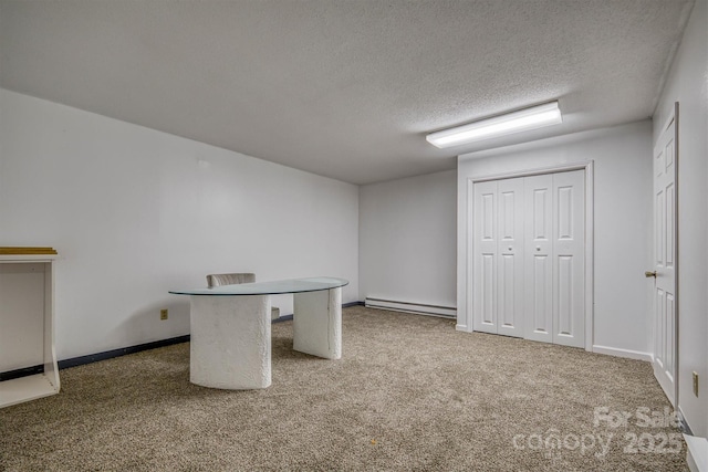 interior space featuring a baseboard heating unit, baseboards, carpet, and a textured ceiling