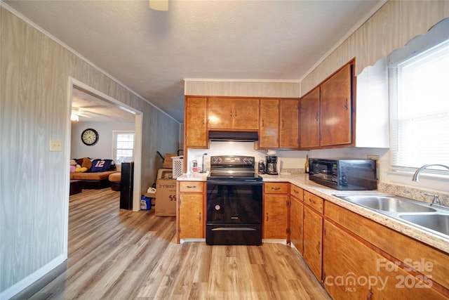 kitchen featuring black appliances, a sink, exhaust hood, brown cabinetry, and light countertops