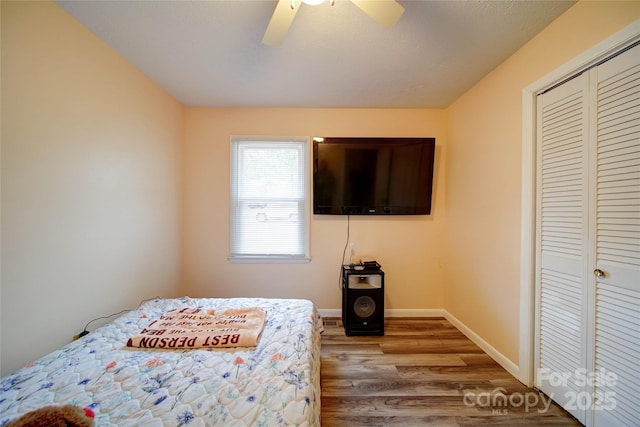 bedroom featuring ceiling fan, a closet, baseboards, and wood finished floors