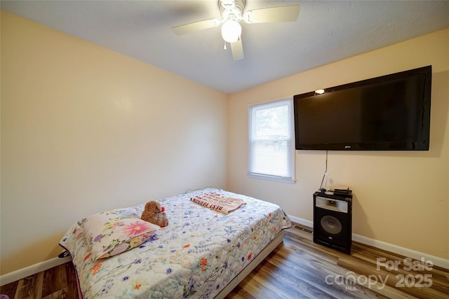 bedroom with ceiling fan, baseboards, and wood finished floors