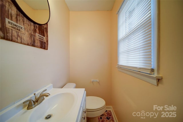 half bath with vanity, toilet, and baseboards