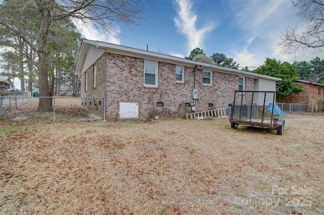 rear view of house featuring a fenced backyard, brick siding, and crawl space