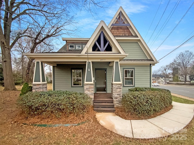 craftsman inspired home featuring stone siding and roof with shingles