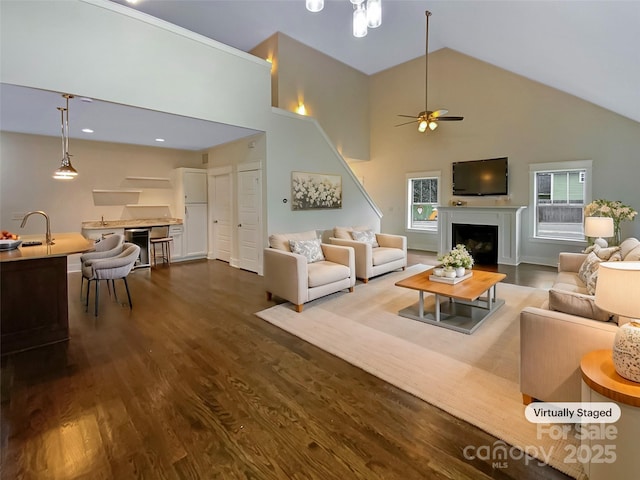 living area featuring dark wood-style floors, a fireplace, high vaulted ceiling, and a healthy amount of sunlight