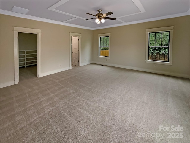 unfurnished bedroom with crown molding, a walk in closet, baseboards, light carpet, and a ceiling fan