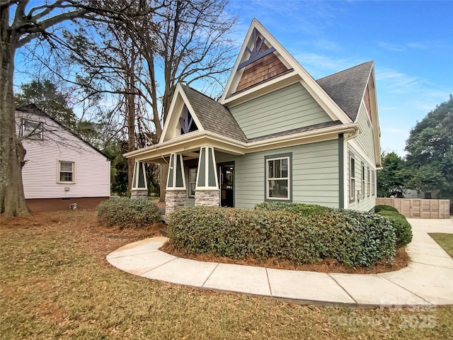 view of front of property featuring fence, stone siding, and a shingled roof