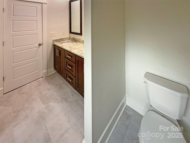 bathroom featuring vanity, toilet, and baseboards