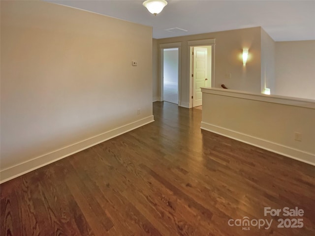 unfurnished room with dark wood-style floors and baseboards