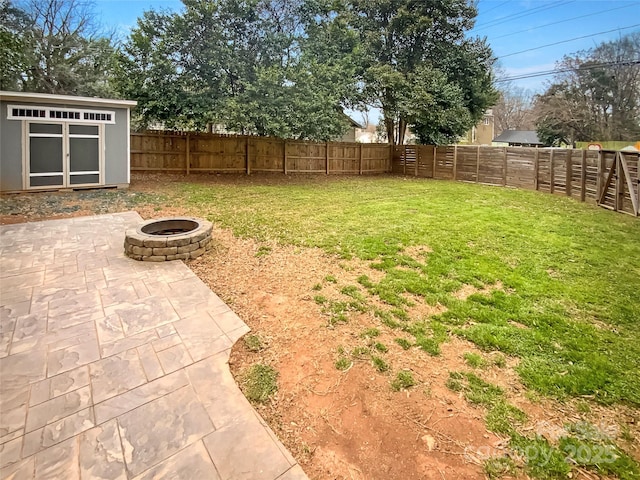 view of yard featuring an outbuilding, a fire pit, a fenced backyard, and a patio area