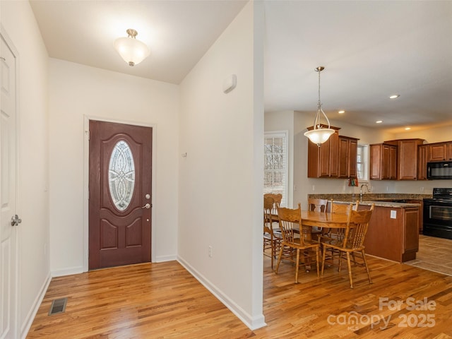 foyer featuring a healthy amount of sunlight, baseboards, visible vents, light wood finished floors, and recessed lighting