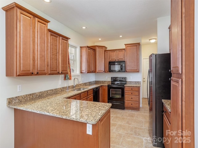 kitchen featuring black appliances, brown cabinetry, a peninsula, and a sink