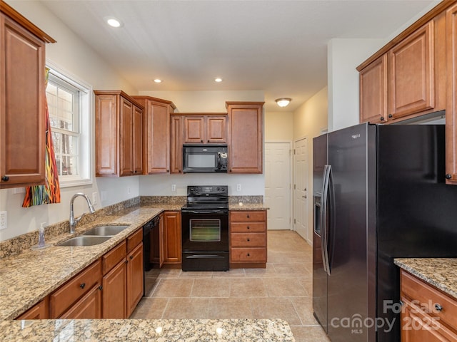 kitchen featuring brown cabinets, black appliances, a sink, light stone counters, and recessed lighting