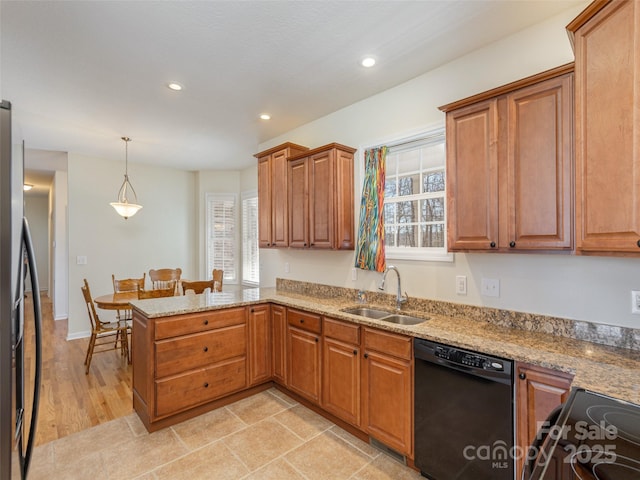 kitchen with brown cabinets, black appliances, a sink, light stone counters, and a peninsula