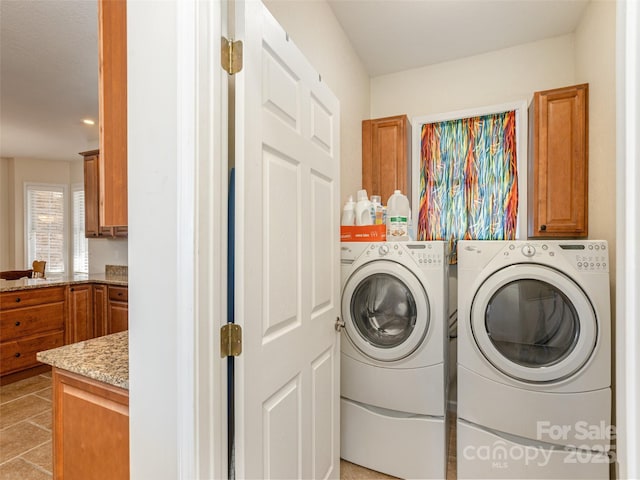 laundry area featuring washer and dryer, light tile patterned floors, and cabinet space