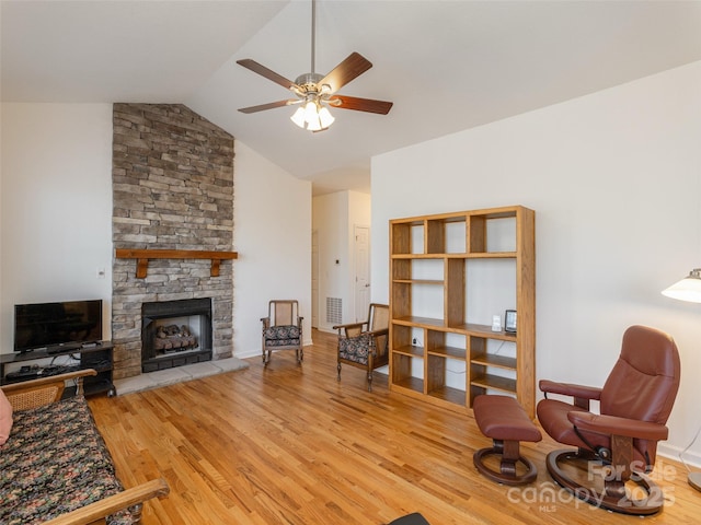 living room featuring wood finished floors, visible vents, lofted ceiling, a fireplace, and ceiling fan