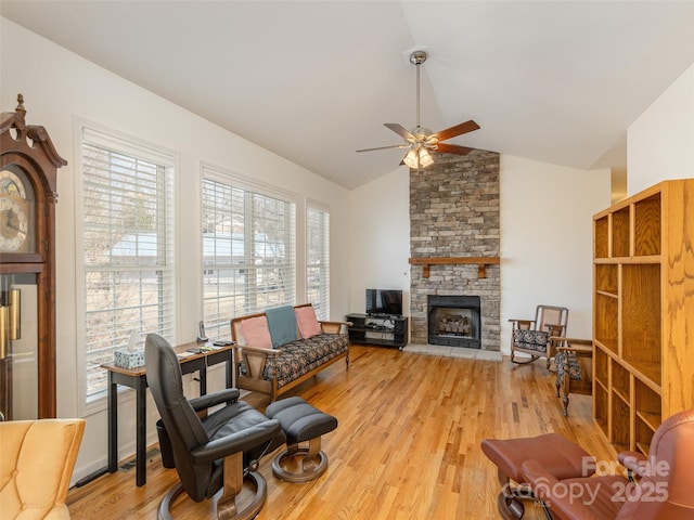 living area featuring light wood finished floors, a fireplace, a ceiling fan, and lofted ceiling