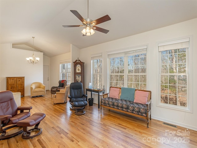 sitting room featuring visible vents, baseboards, vaulted ceiling, ceiling fan with notable chandelier, and light wood-type flooring