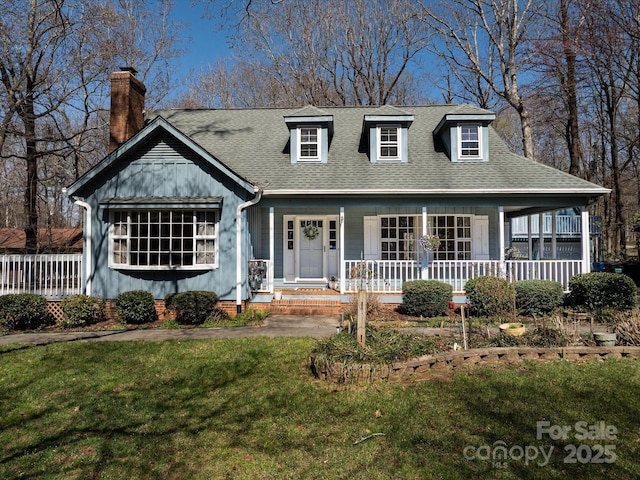 view of front of house featuring a porch, a front lawn, roof with shingles, and a chimney