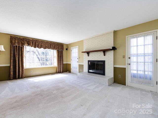 unfurnished living room featuring carpet floors and a brick fireplace