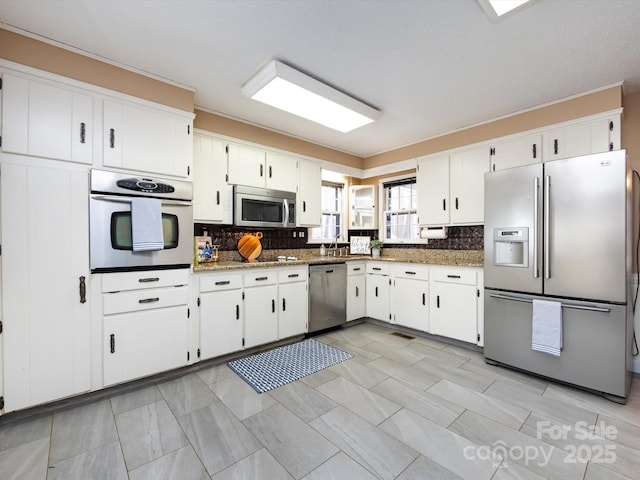 kitchen with stone counters, stainless steel appliances, decorative backsplash, and white cabinetry