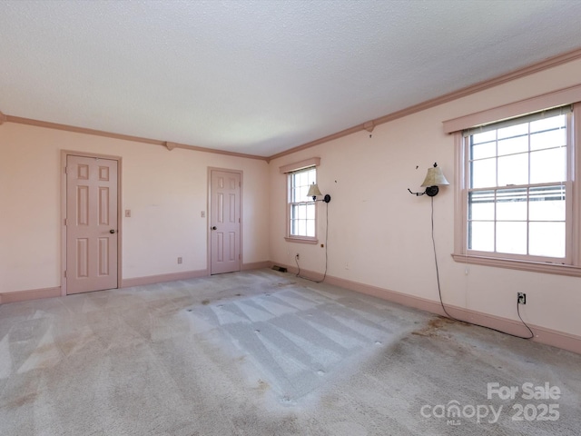 spare room with baseboards, light carpet, a textured ceiling, and ornamental molding