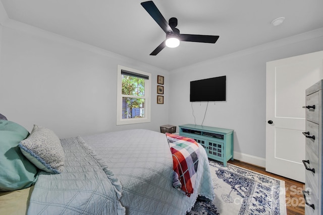 bedroom with baseboards, crown molding, ceiling fan, and wood finished floors