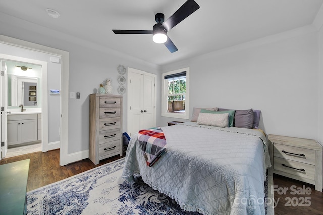 bedroom featuring a ceiling fan, a sink, wood finished floors, a closet, and baseboards