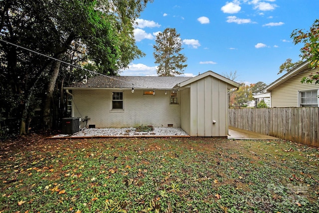 rear view of property featuring brick siding, board and batten siding, fence, central AC, and crawl space